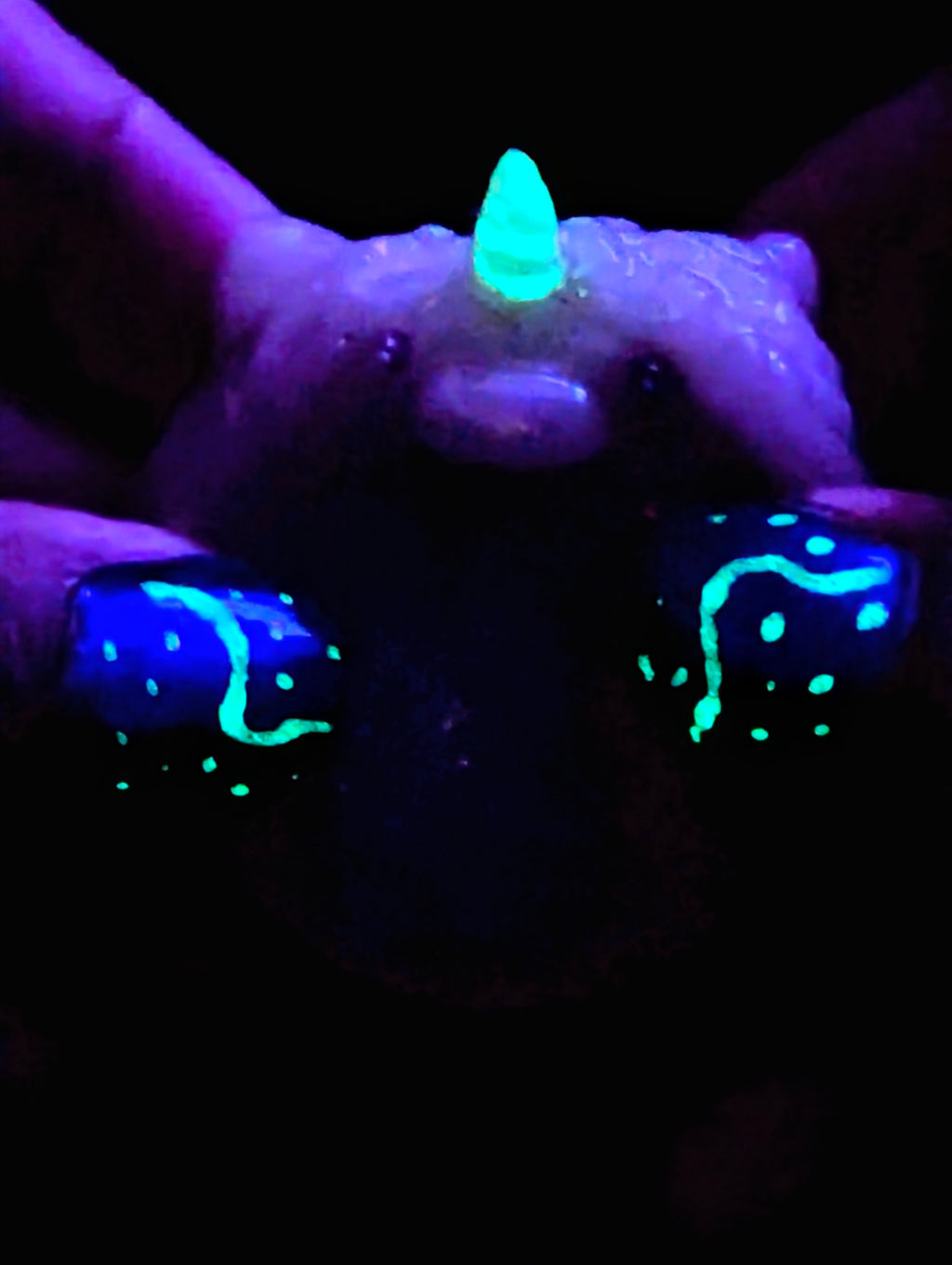 Hands holding clay unicorn worry stone hand made from polymer clay for comfort and control stress and anxiety the unicorn horn glowing in the dark