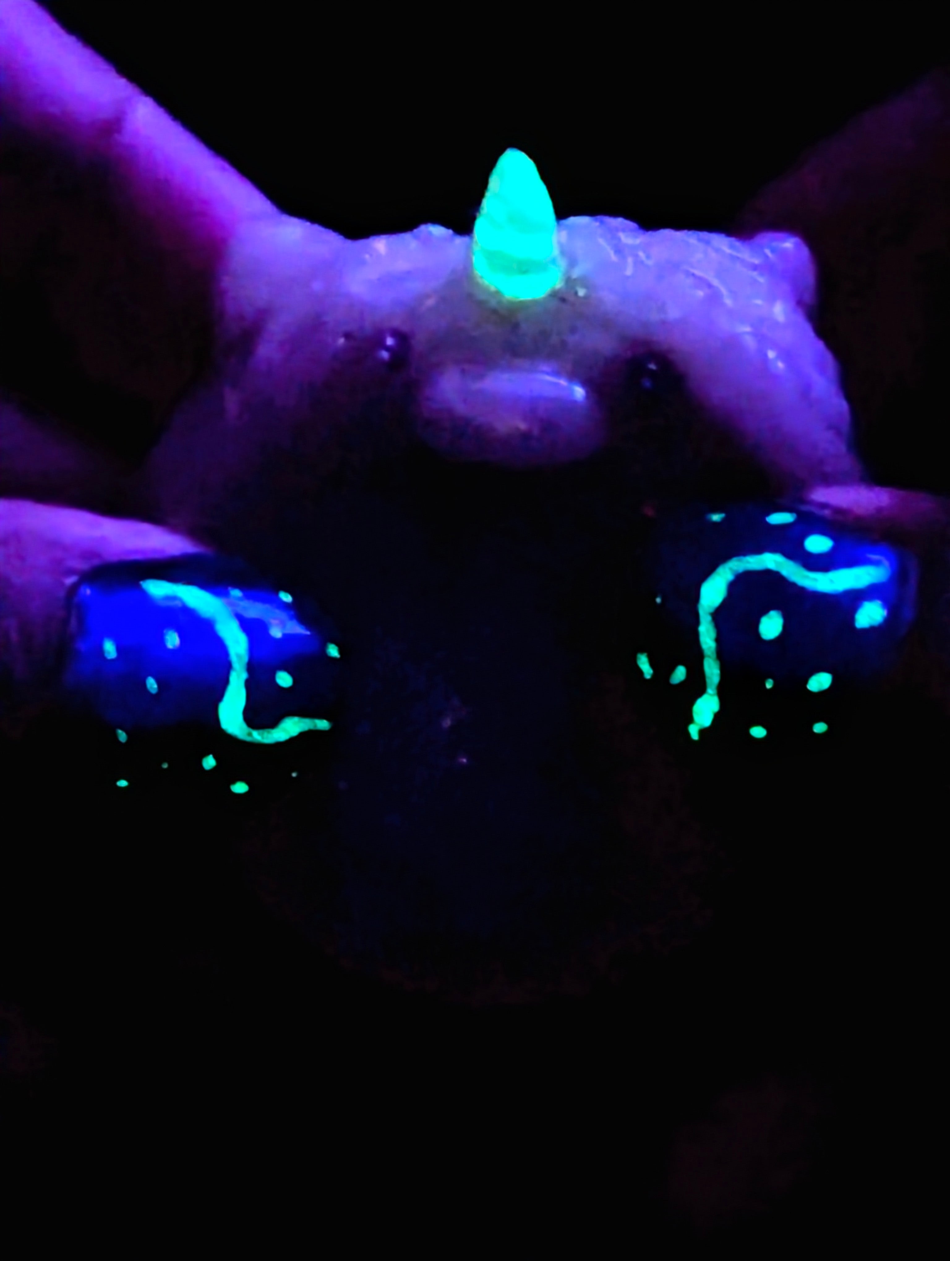 Hands holding clay unicorn worry stone hand made from polymer clay for comfort and control stress and anxiety the unicorn horn glowing in the dark